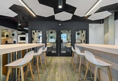 Bright breakout space featuring minimalist white stools and geometric ceiling lighting.
