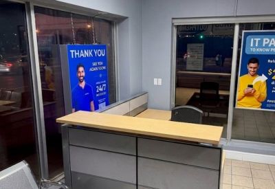Close-up of a modern grey and wood reception desk with a black office chair in the background.