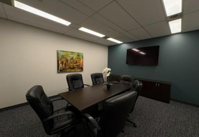 Professional meeting room featuring a dark wood table, black leather chairs, and a wall-mounted TV.
