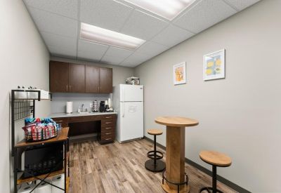 Breakroom with dark wood cabinets, a white refrigerator, and a high-top cafe table.