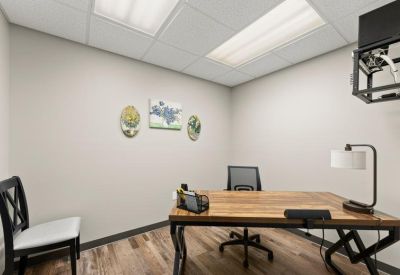 Private office featuring a large wooden desk, ergonomic chair, and minimalist wall art.