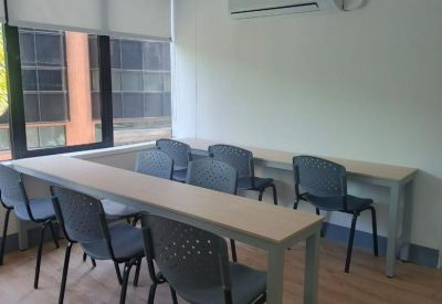 Classroom-style training room with rows of light wood tables and grey chairs.