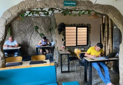 Indoor coworking area with stone-textured walls and patrons working at modern minimalist desks.