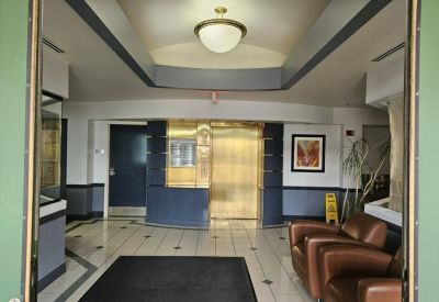 Modern lobby area with leather armchairs and a gold-accented elevator bank.