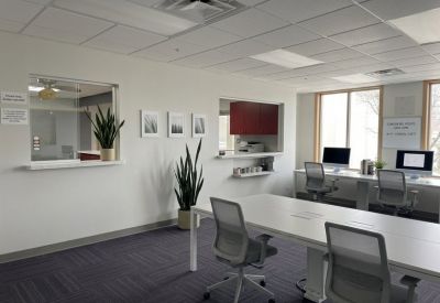 Bright coworking area with workstations, indoor plants, and a service window.