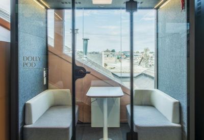Private glass-walled meeting pod with gray benches and a small central table.