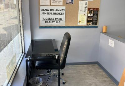 Single desk and chair by a large window next to a decorative Welcome bulletin board.