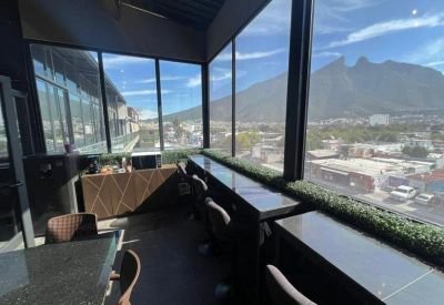 Modern communal cafe area with high-top seating and floor-to-ceiling windows overlooking mountains.