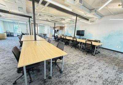 Spacious open-plan workspace featuring long wooden desks and ergonomic chairs.