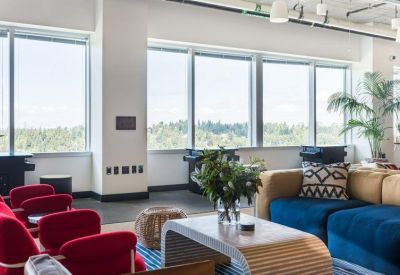 Lounge area with vibrant red armchairs and blue velvet sofa overlooking trees.
