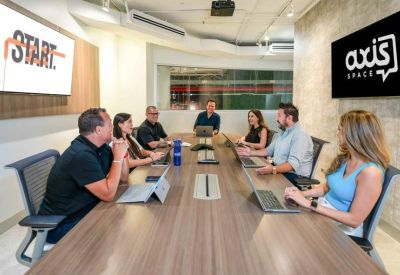 Bright conference room with people seated around a long wooden table.