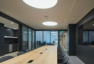 Bright open-plan workspace with rows of desks and industrial ceilings.