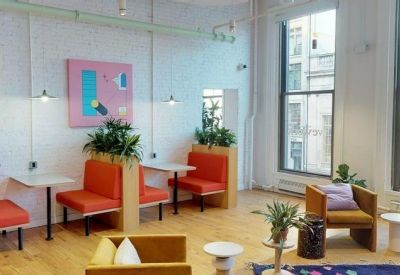 Bright coworking area featuring orange booth seating, wooden floors, and vibrant wall art.