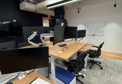 Modern workspace featuring height-adjustable desks with dual monitor setups.