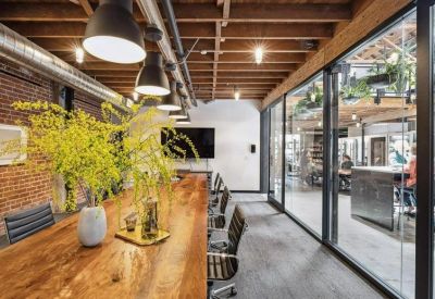 Long wooden conference table beside an exposed brick wall with industrial lighting.