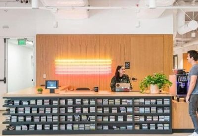 Modern reception desk with a vibrant glowing orange feature wall and wooden accents.