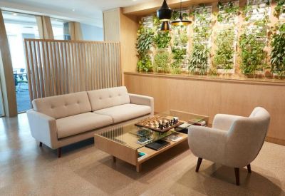 Bright breakout space featuring a large sofa, glass coffee table, and a lush vertical garden wall.