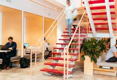 Contemporary workspace with built-in booths and a vibrant red-tread staircase.