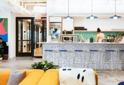Modern office pantry and cafe area with a stone-textured breakfast bar and colorful wall art.