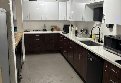Modern galley kitchen with dark lower cabinets, white upper cabinets, and integrated appliances.