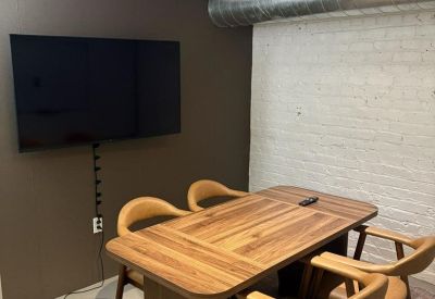 Private meeting space with a wood-grain table, tan chairs, and a dark accent wall.