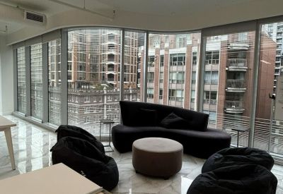 Sunlit lounge area with a curved sofa, bean bags, and panoramic city views.