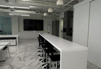 White high-top breakfast bar with black stools in a modern communal kitchen area.
