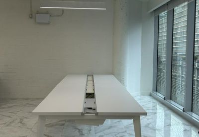 Sleek white workstation desk on a marble floor in a bright office space.
