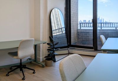 Bright office space with a full-length arched mirror, potted plant, and green desks.