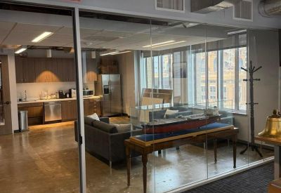 Modern breakout area with a sleek kitchen, lounge seating, and a model ship display.