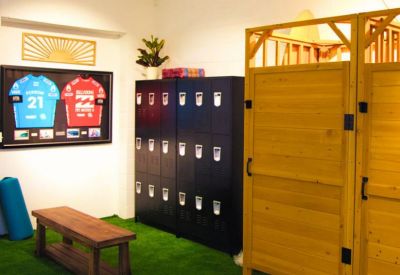 Changing room area with black lockers, a wooden bench, and artificial turf flooring.