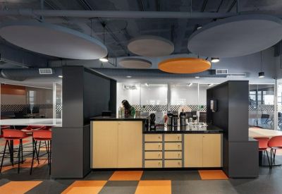 Modern office kitchen and breakout area with wooden cabinets and orange tiled floor.