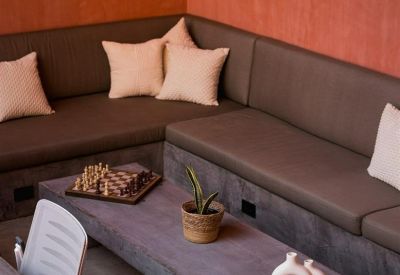 Corner of a built-in sofa area with throw pillows and a wooden coffee table with a chess set.