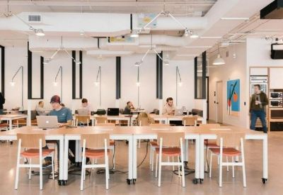 Spacious communal work area with long wooden tables and rows of chairs.