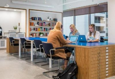 Communal workspace with a blue-topped long table, bookshelves, and integrated storage drawers.