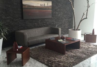 Lounge area with a dark textured feature wall, grey sofa, and plush rug.