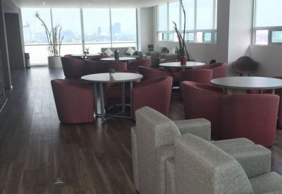 Spacious cafe-style breakout area with red tub chairs and large windows.