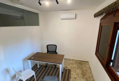Bright workspace with a wooden desk, striped rug, and wall-mounted air conditioner.