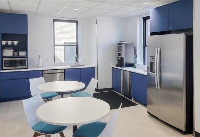 Modern breakroom kitchen with blue cabinetry and stainless steel appliances.