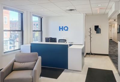 Branded reception desk in blue and white with large windows.