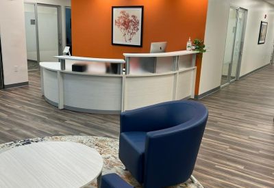 Bright reception area featuring a curved white desk against a vibrant orange accent wall.