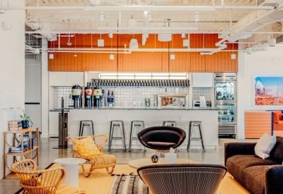 Modern office kitchen and bar area with stylish bar stools and a sleek white counter.
