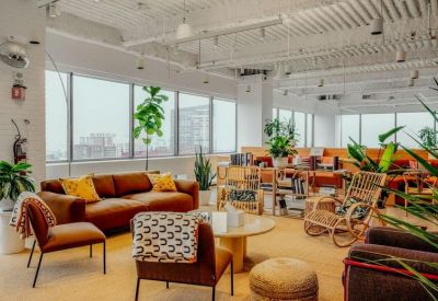 Bright breakout space with brown leather sofas, armchairs, and large windows overlooking the city.