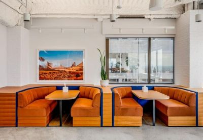 Symmetrical orange velvet booth seating with wooden tables and a large landscape wall art piece.