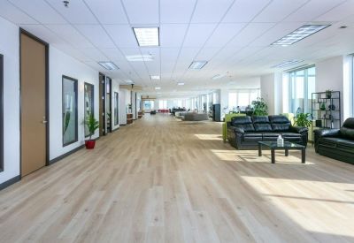 Expansive communal lounge with black leather sofas and light wood floors.