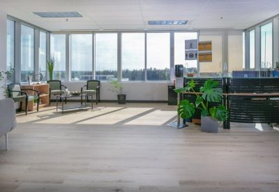 Bright reception area with wood flooring, indoor plants, and large windows.