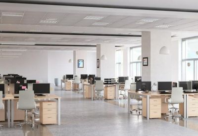 Open-plan office with rows of wooden desks and computers.
