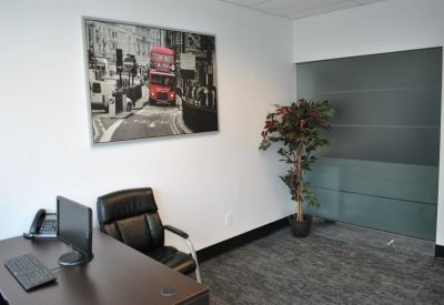 Private office with a dark wood desk, black leather chair, and London-themed wall art.