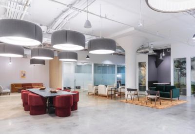 Spacious coworking lounge with red tub chairs and large gray pendant lights.