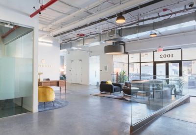 Bright reception area with a wood desk, yellow velvet chair, and glass railing.